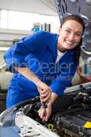 Smiling mechanic working under the bonnet