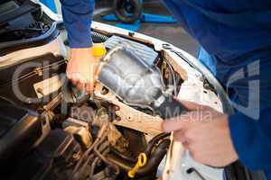 Mechanic examining under hood of car with torch