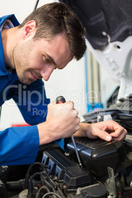 Mechanic using screwdriver on engine