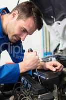 Mechanic using screwdriver on engine