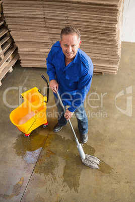 Smiling man moping warehouse floor