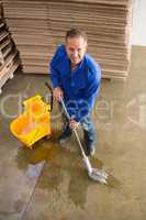 Smiling man moping warehouse floor