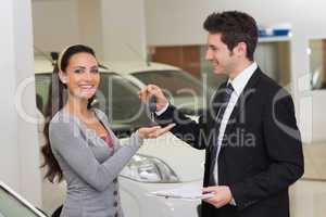 Smiling businessman giving car key to happy customer