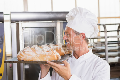 Baker holding tray of bread