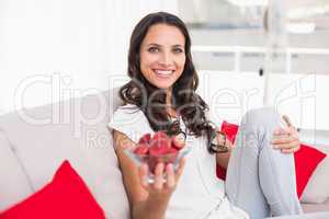 Pretty brunette eating strawberries on couch