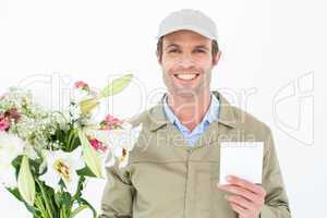 Happy delivery man with bouquet showing blank note