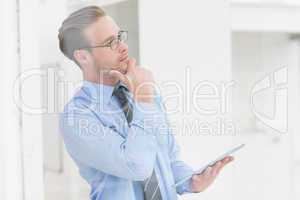 Thoughtful businessman hand on chin holding tablet
