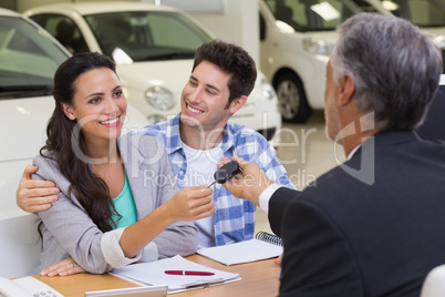 Salesman giving car keys to a couple