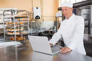 Focused baker using laptop on worktop