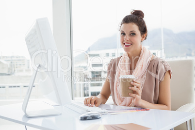 Smiling businesswoman holding paper cup of coffee