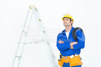 Thoughtful electrician with arms crossed by ladder