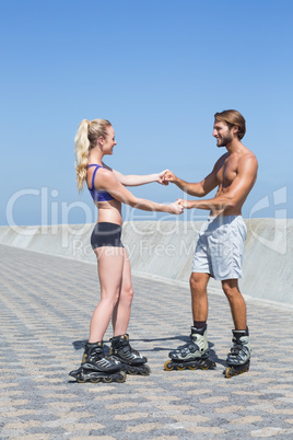 Fit couple rollerblading together on the promenade