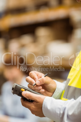 Close up of manager wearing yellow vest using handheld