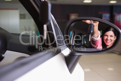 Woman showing car key in rear view mirror