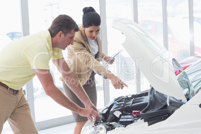 Businesswoman and customer looking at a car engine