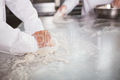 Close up of bakers kneading dough at counter