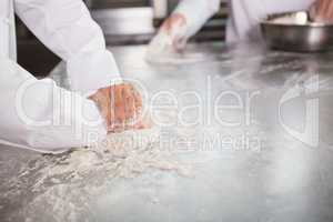 Close up of bakers kneading dough at counter