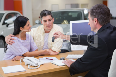 Salesman giving car keys to a couple