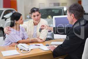 Salesman giving car keys to a couple