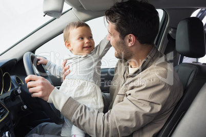 Father playing with baby in drivers seat