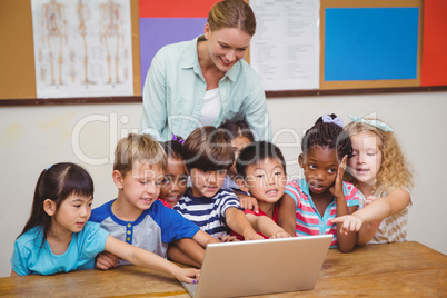 Teacher and pupils looking at laptop