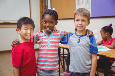 Cute pupils smiling at camera in classroom