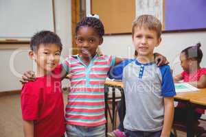 Cute pupils smiling at camera in classroom