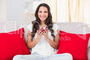 Pretty brunette eating strawberries on couch