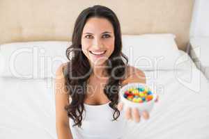 Pretty brunette offering candy in bed