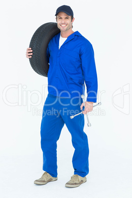 Confident mechanic carrying tire
