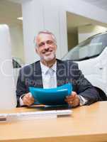 Smiling businessman holding a folder at his desk