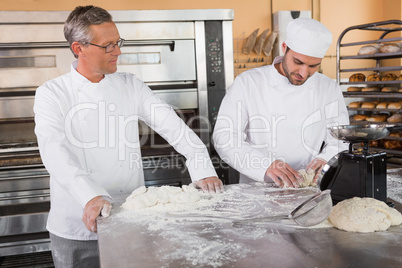 Baker looking his colleague kneading dough