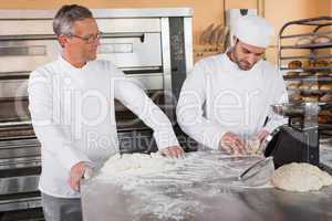 Baker looking his colleague kneading dough