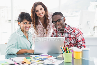 Smiling teamwork with laptop looking at camera