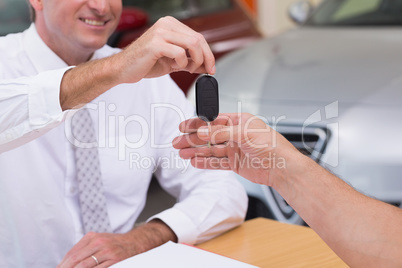 Smiling salesman giving a customer car keys