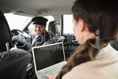 Young businesswoman being chauffeured while working