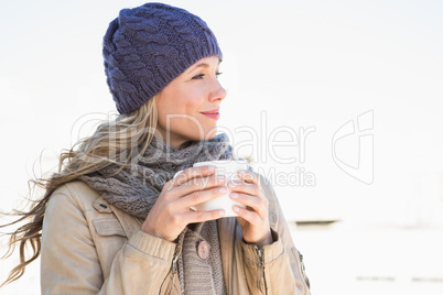 Thoughtful blonde in warm clothes holding hot beverage