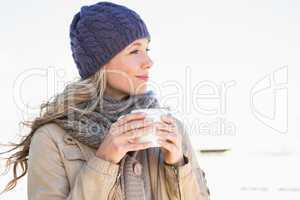 Thoughtful blonde in warm clothes holding hot beverage
