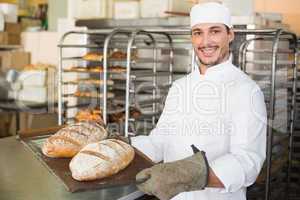 Happy baker holding tray of fresh bread