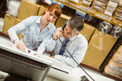 Manager working on laptop and talking on phone at desk