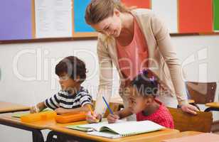 Cute pupil getting help from teacher in classroom