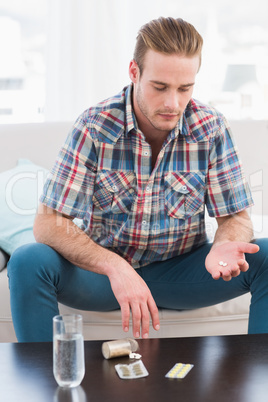 Hungover man with his medicine laid on coffee table