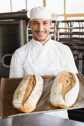 Happy baker showing tray of fresh bread