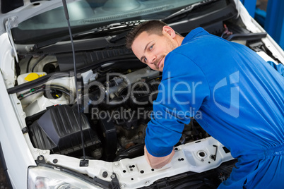 Mechanic smiling at the camera fixing engine