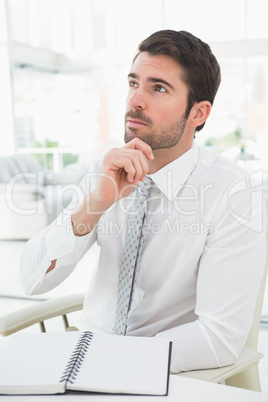 Elegant businessman sitting at desk thinking