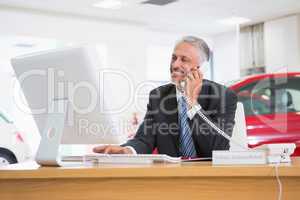 Smiling businessman using laptop on the phone