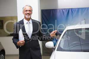 Smiling businessman holding car key and folder