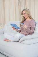 Smiling blonde shopping online with tablet