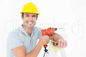 Happy technician holding drill machine while leaning on ladder