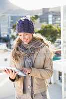 Smiling blonde in warm clothes using tablet